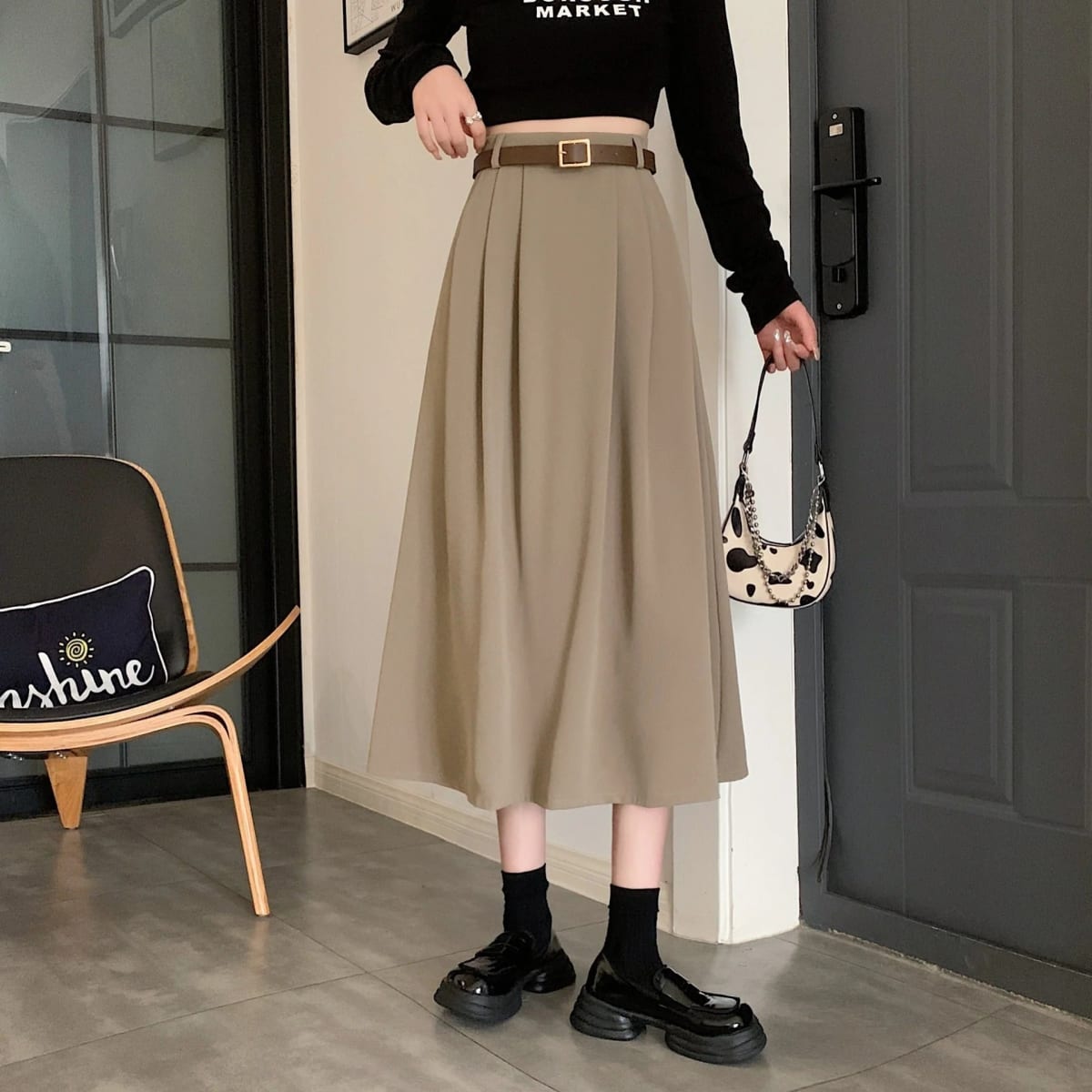Model wearing high-waisted pleated A-line midi skirt with belt.