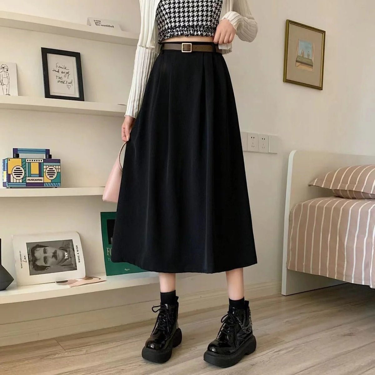 Model wearing high-waisted pleated A-line midi skirt with belt.