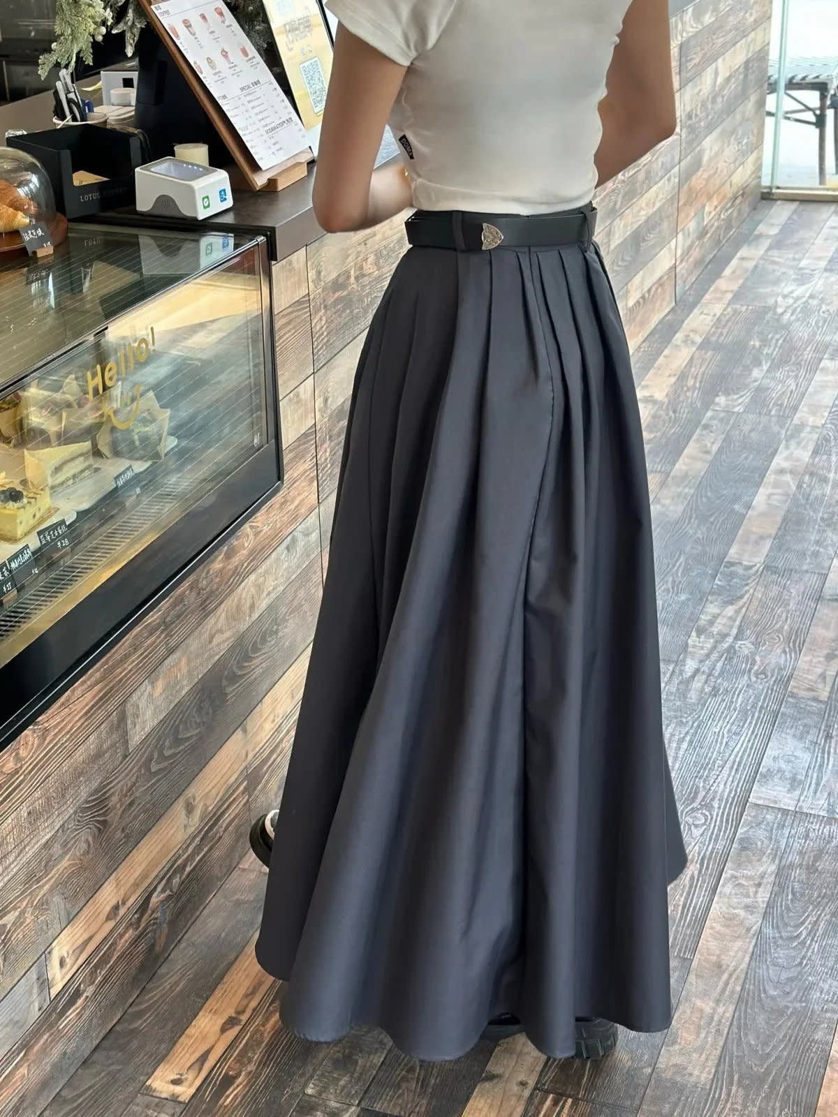 Back view of a person wearing a pleated maxi skirt with a belt.