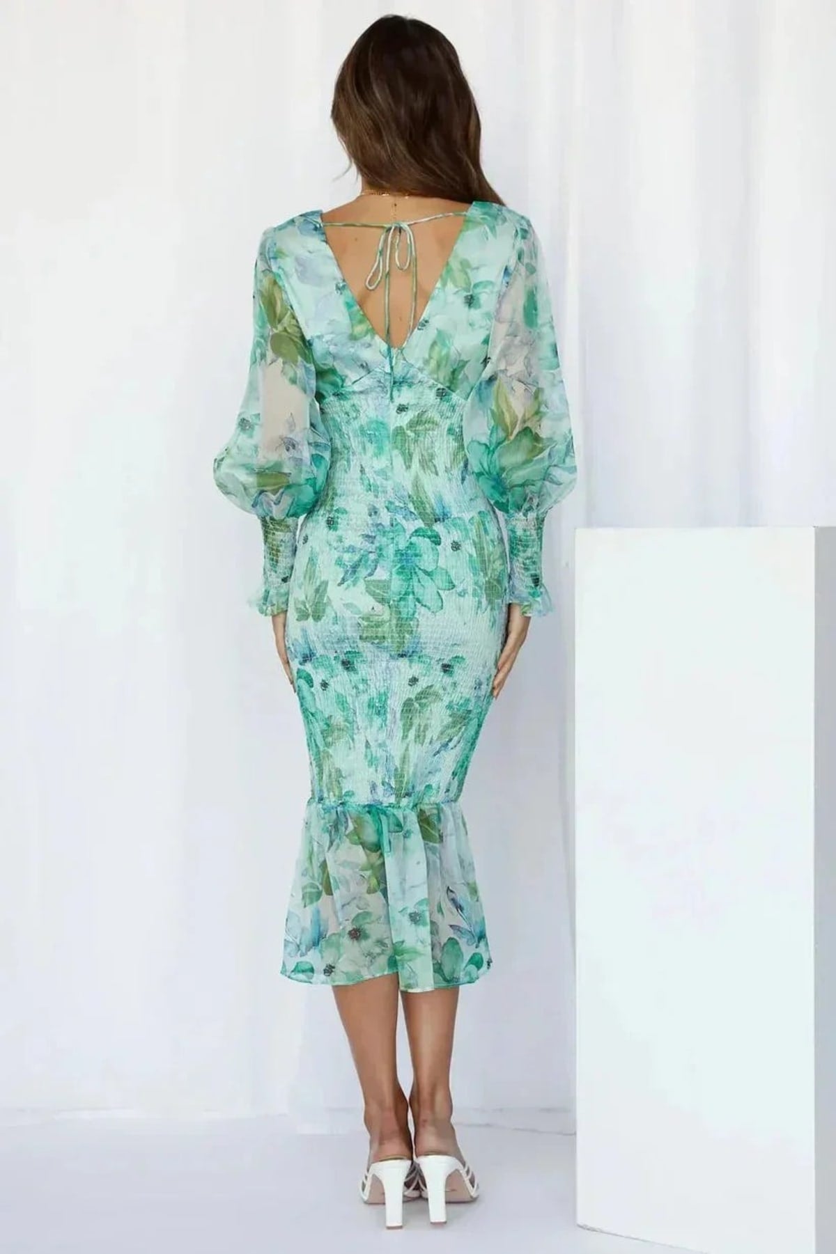 Woman wearing floral midi dress with smocked bodice and long sleeves.