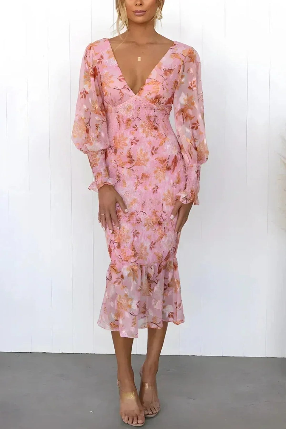 Woman wearing floral midi dress with smocked bodice and long sleeves.