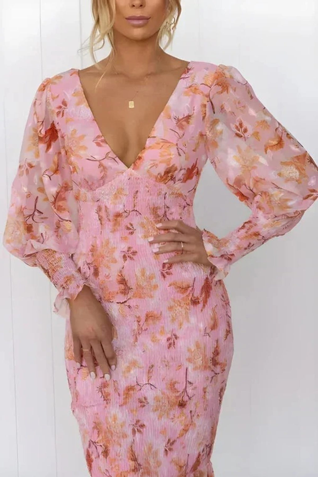 Woman wearing floral midi dress with smocked bodice and long sleeves.