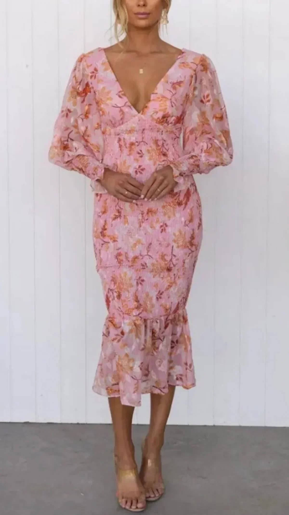 Woman wearing floral midi dress with smocked bodice and long sleeves.
