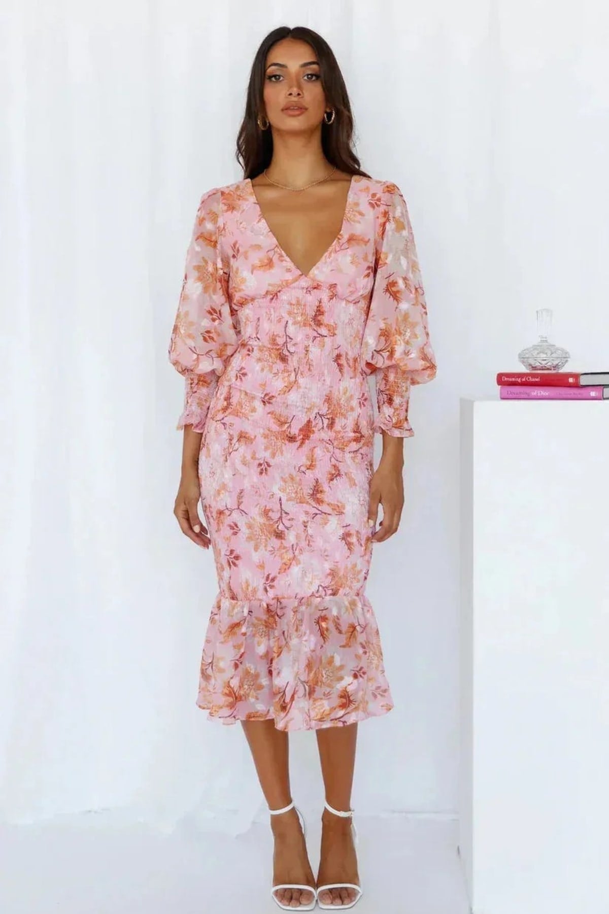 Woman wearing floral midi dress with smocked bodice and long sleeves.
