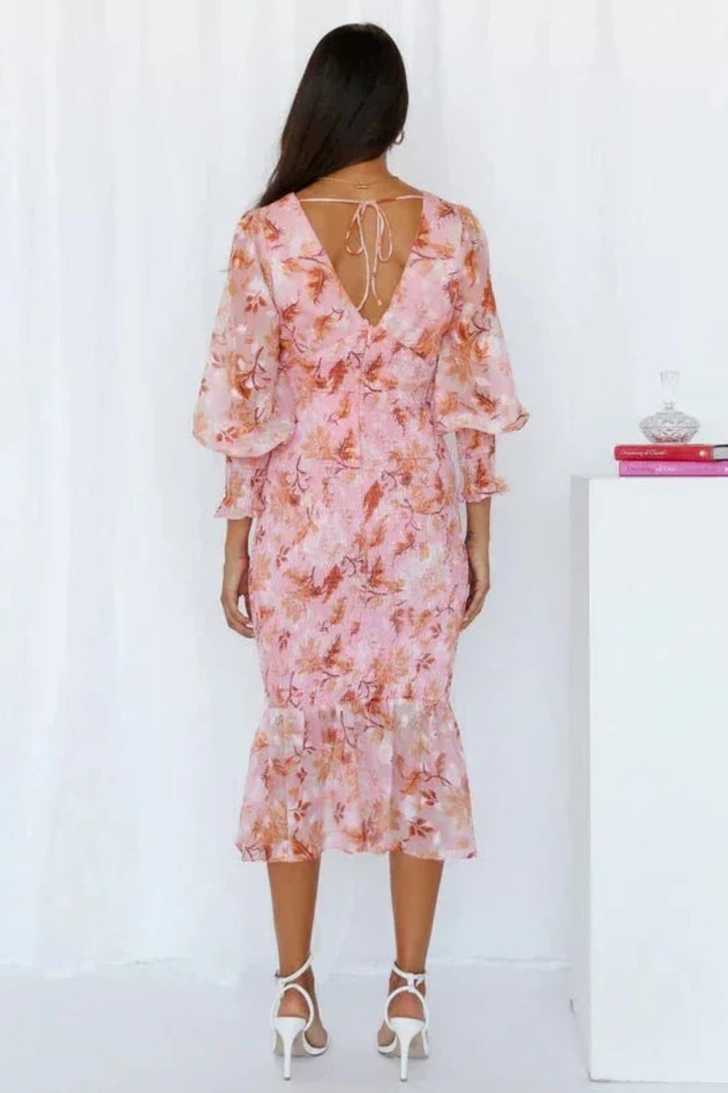 Woman wearing floral midi dress with smocked bodice and long sleeves.