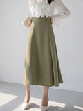 Woman wearing a high-waisted A-line midi skirt with a blouse.