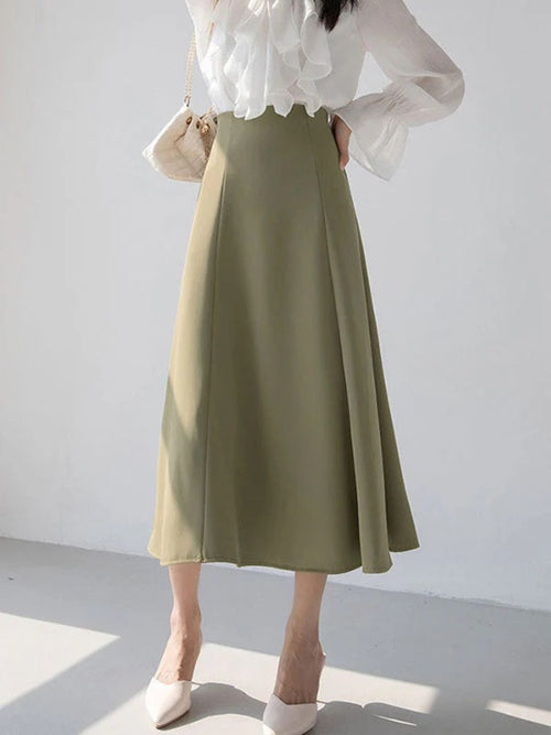 Woman wearing a high-waisted A-line midi skirt with a blouse.