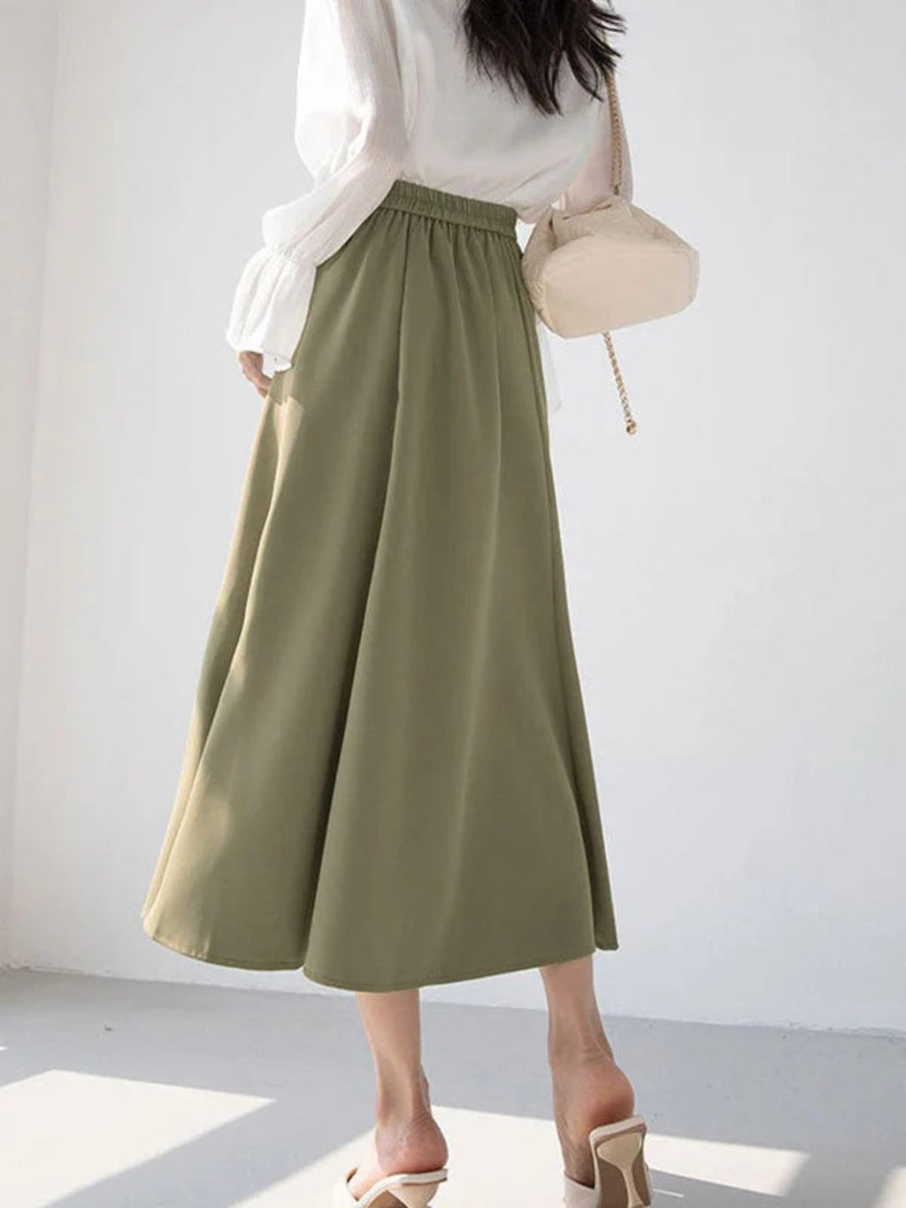 Woman wearing a high-waisted A-line midi skirt with a blouse.
