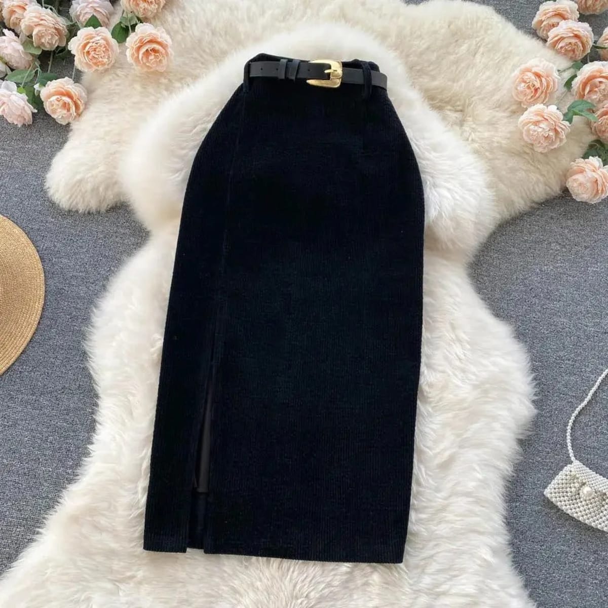Beige corduroy midi skirt with front slit on white rug.