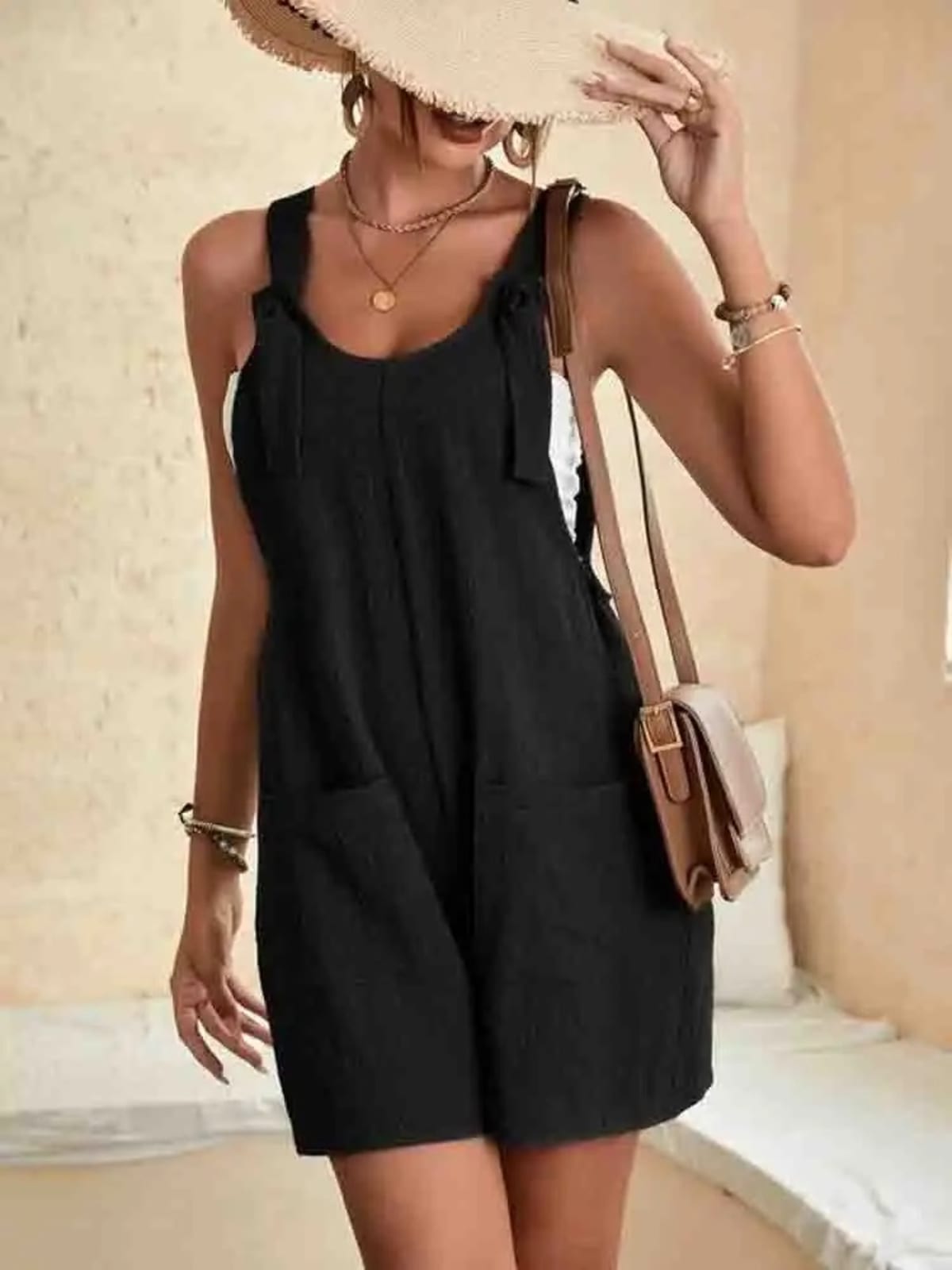 Women's romper with tie-strap shoulders and front pockets.