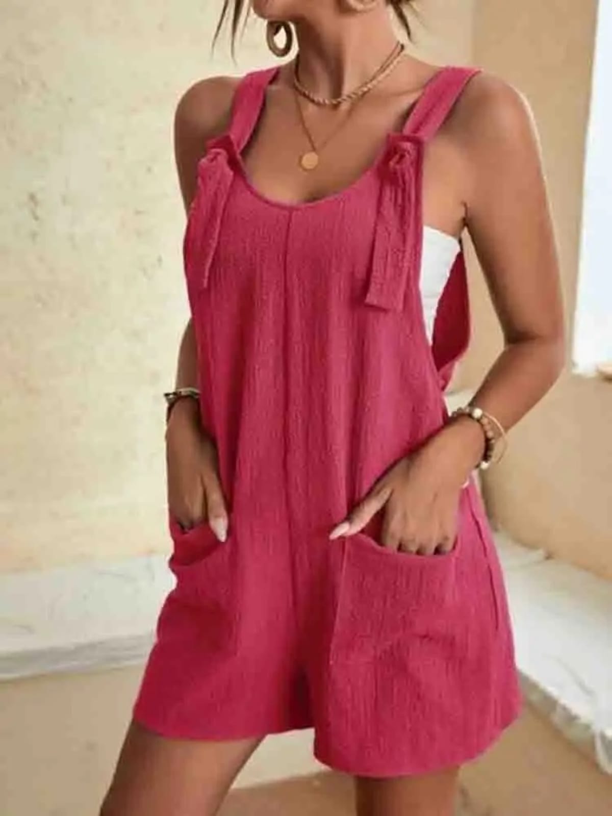 Women's romper with tie-strap shoulders and front pockets.