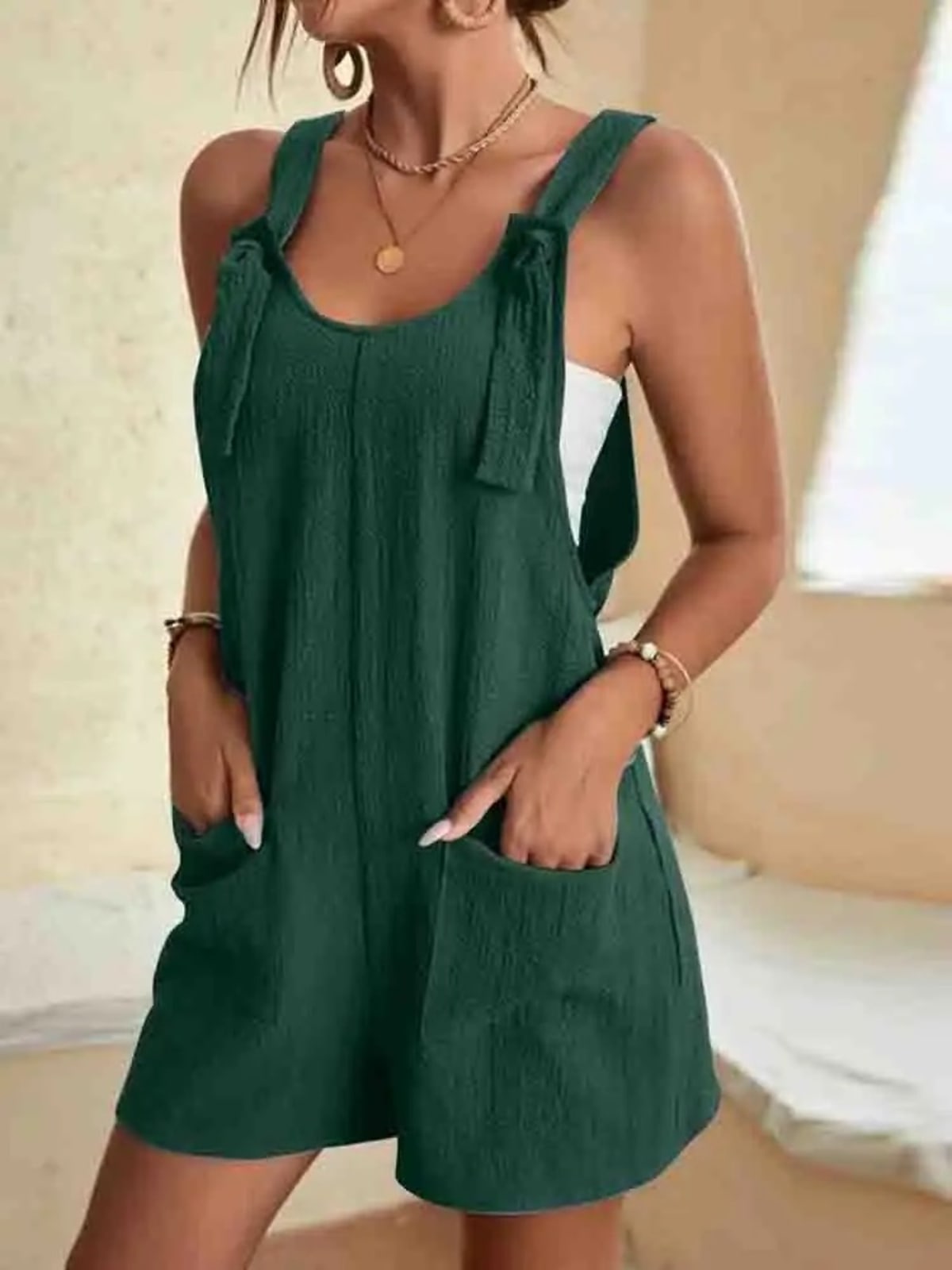 Women's romper with tie-strap shoulders and front pockets.