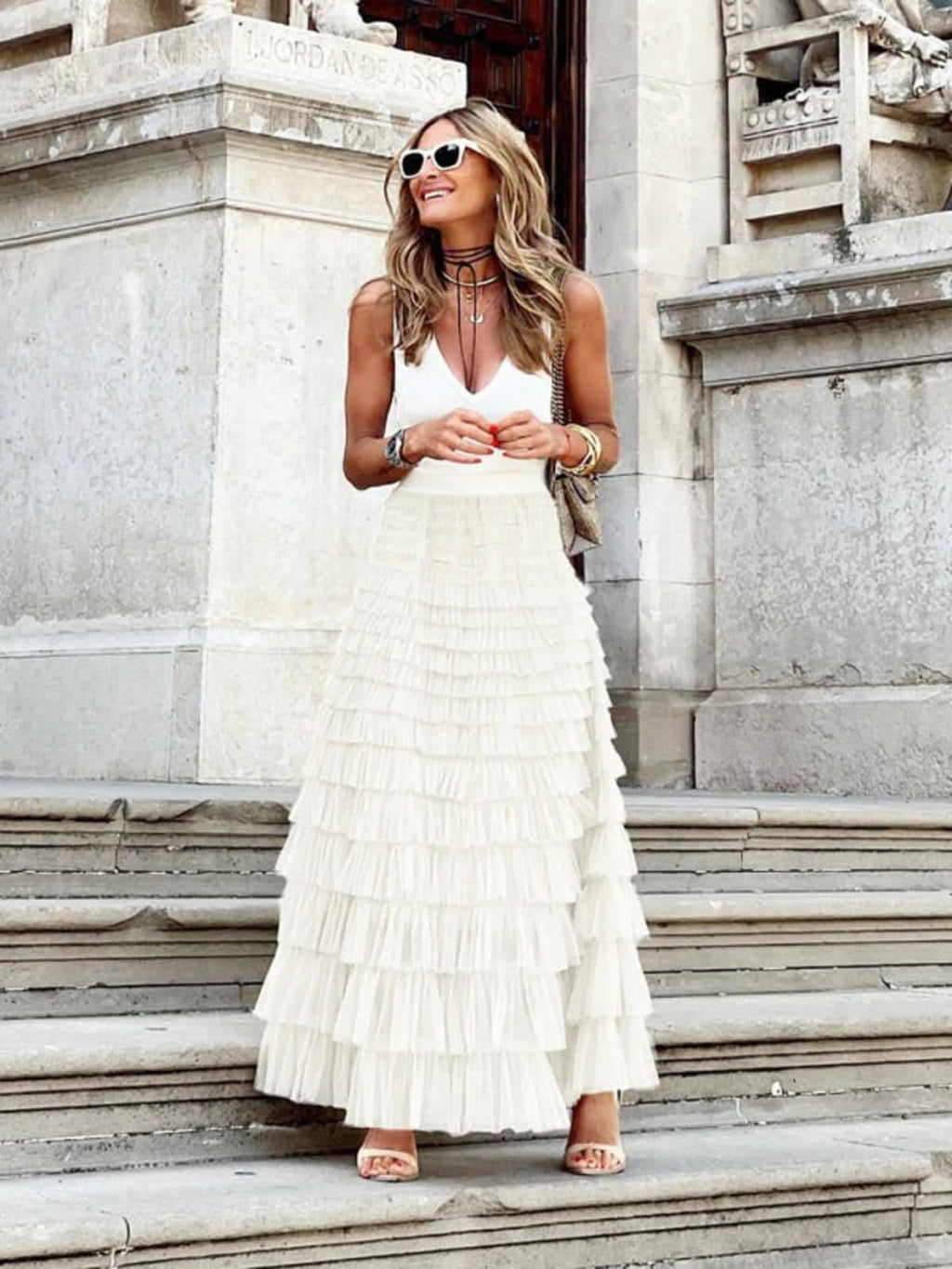 Woman in off-white tiered maxi skirt with ruffles.