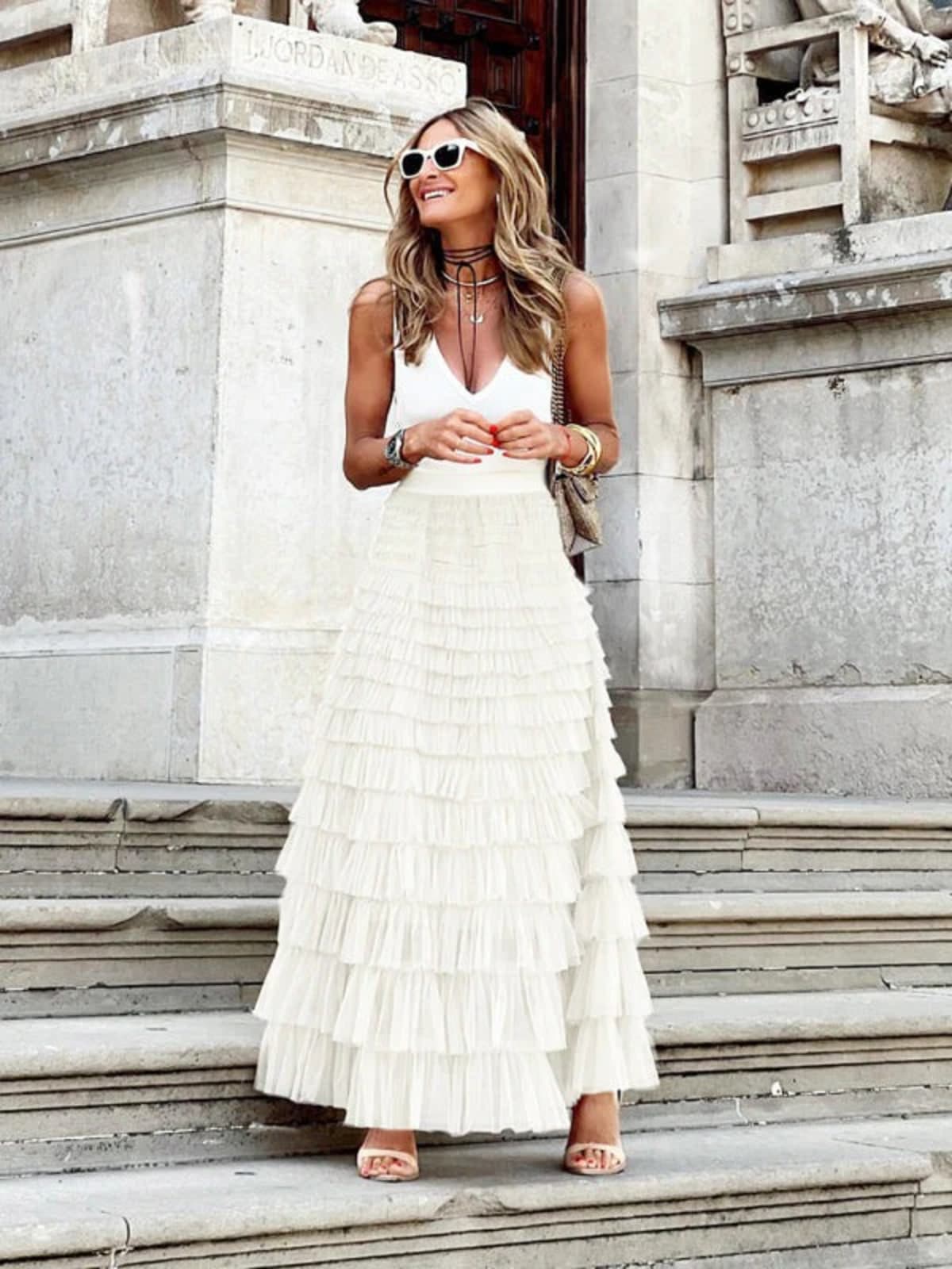 Woman in off-white tiered maxi skirt with ruffles.