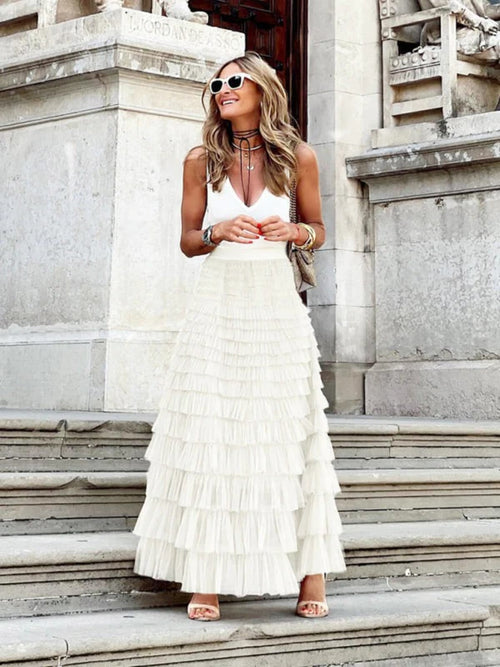 Woman in off-white tiered maxi skirt with ruffles.