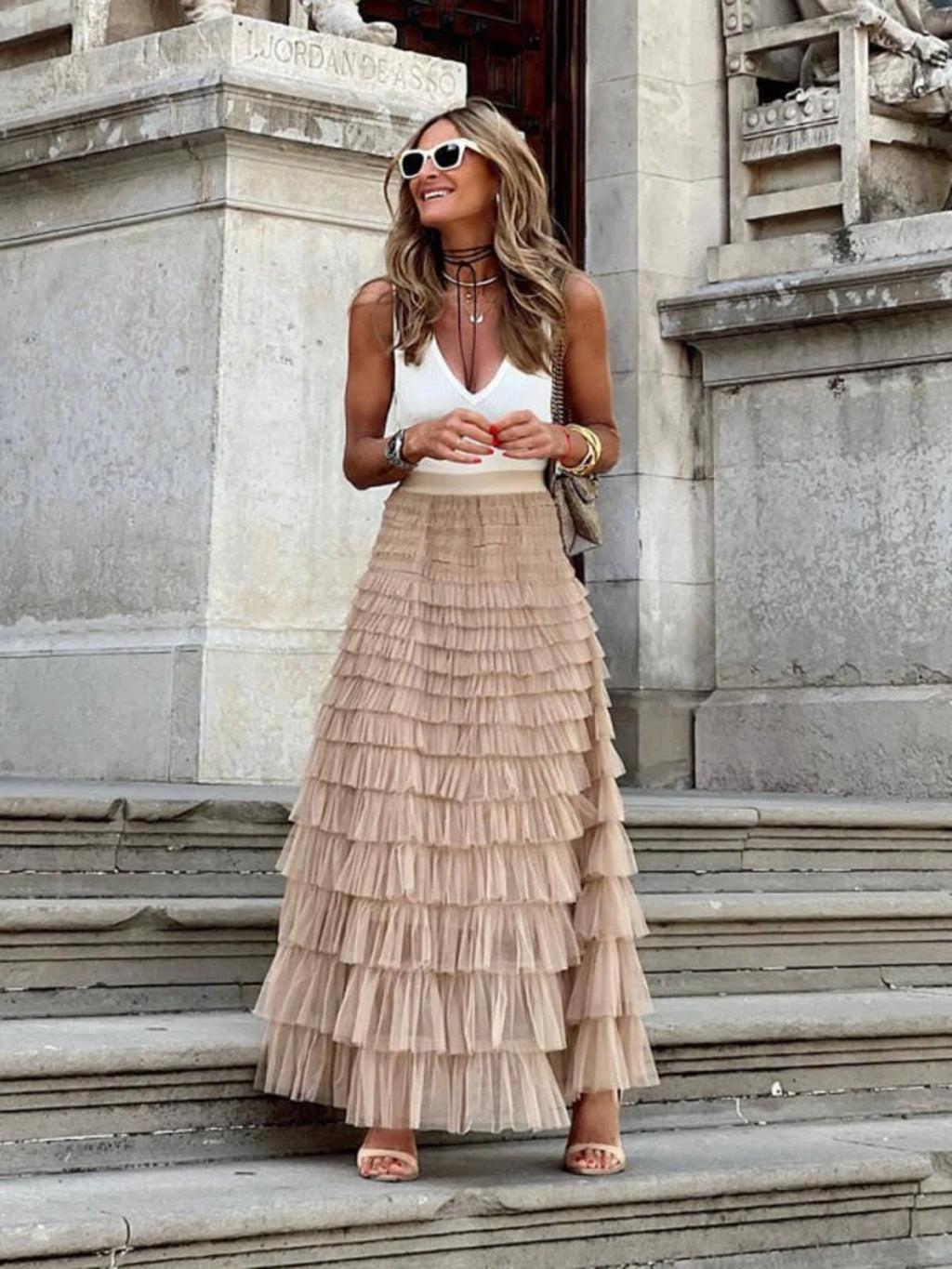Woman in off-white tiered maxi skirt with ruffles.
