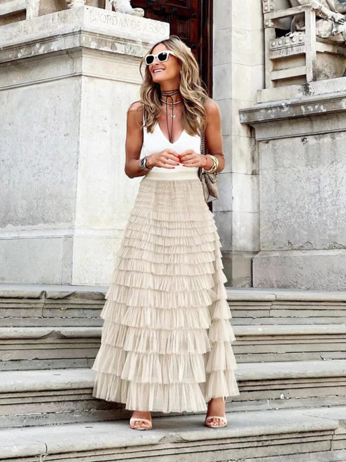 Woman in off-white tiered maxi skirt with ruffles.