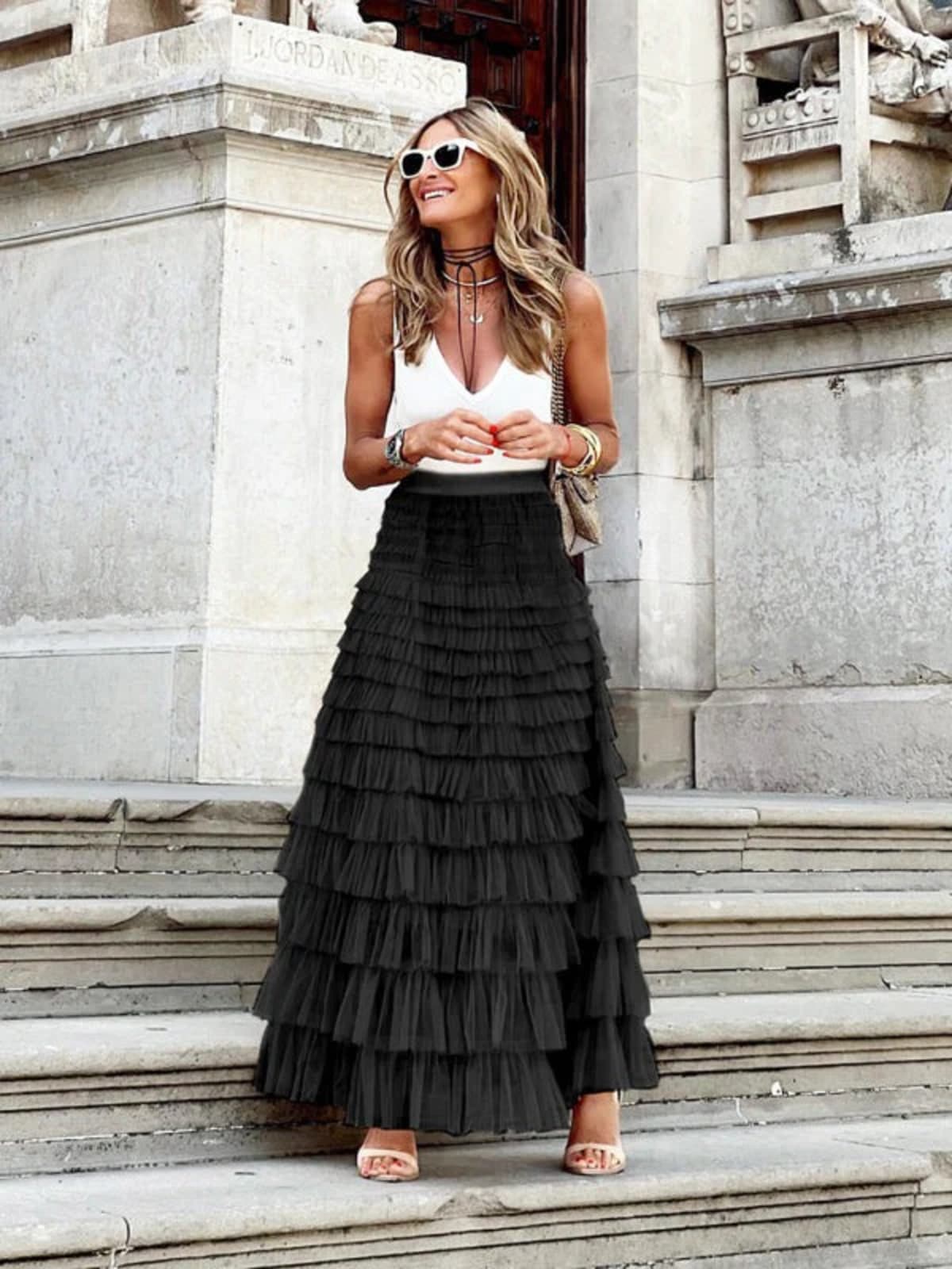 Woman in off-white tiered maxi skirt with ruffles.