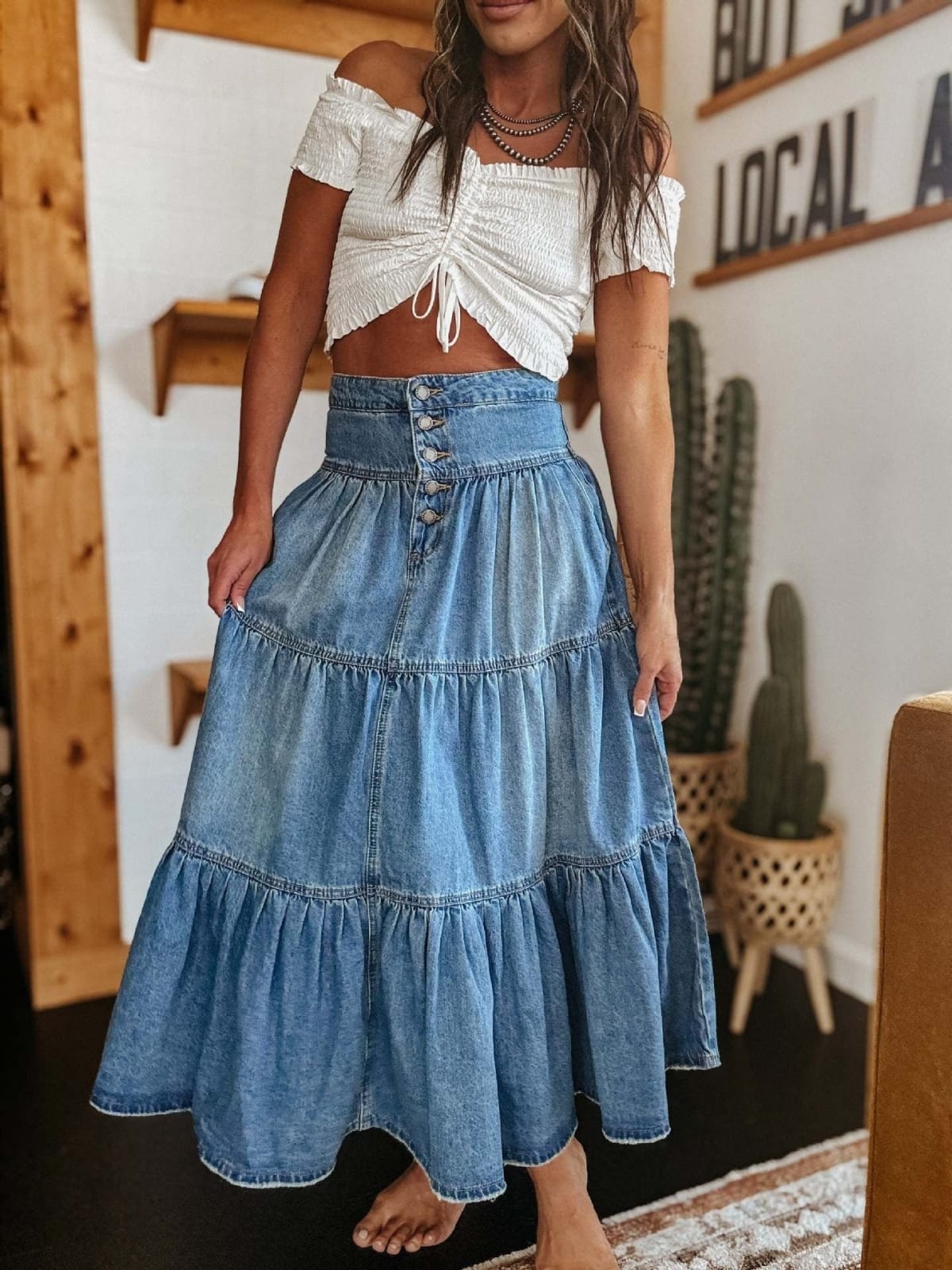 Woman in tiered denim maxi skirt with button-front and off-shoulder top.