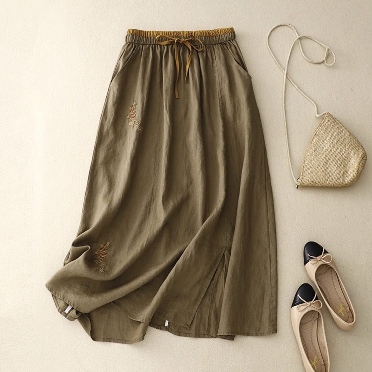 Light beige midi skirt with drawstring waist and embroidery.
