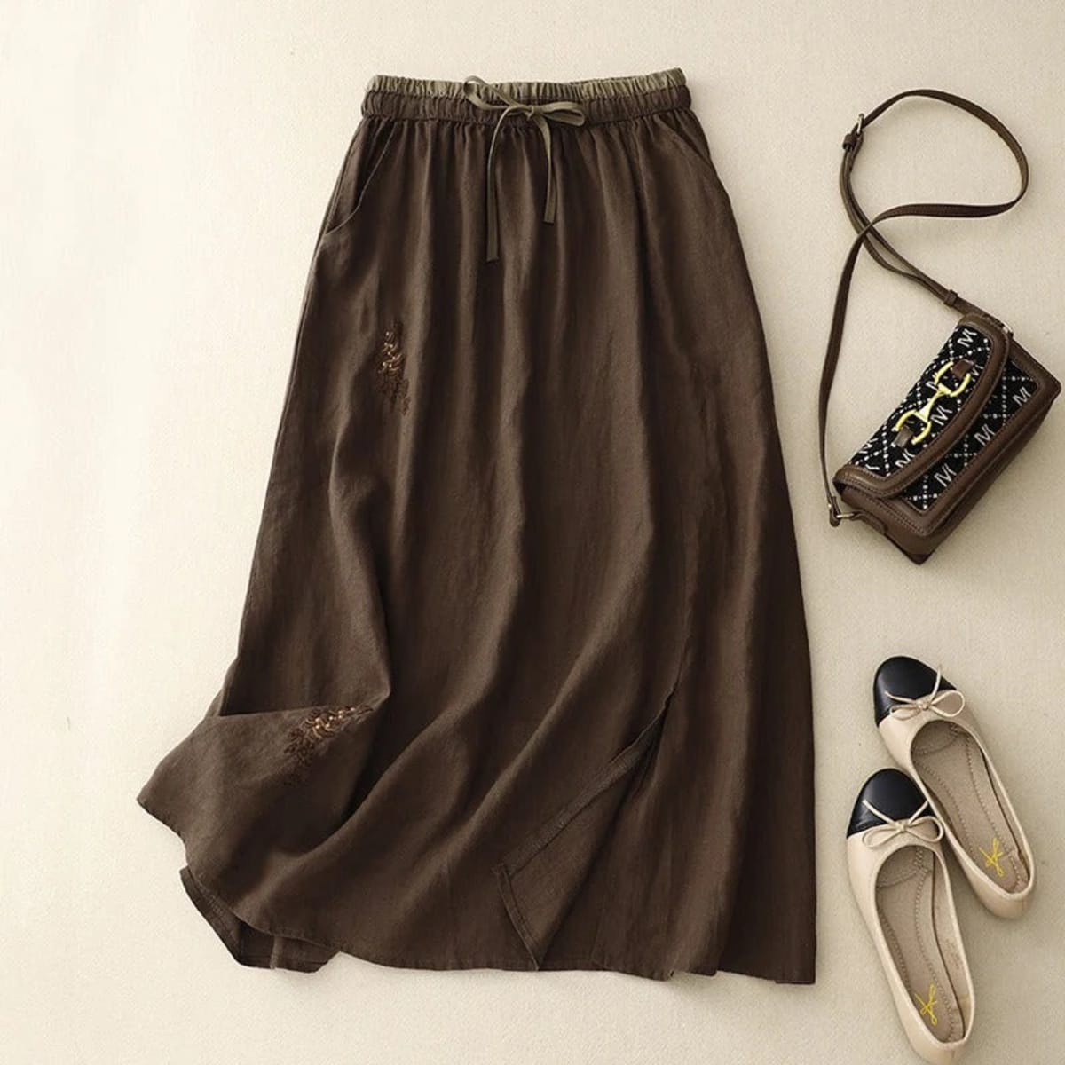 Light beige midi skirt with drawstring waist and embroidery.