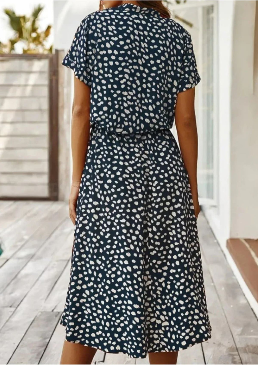 Woman in a spot print midi shirt dress with short sleeves and drawstring waist.