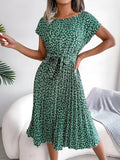 A-line dress with pleated skirt and floral pattern, worn outdoors.