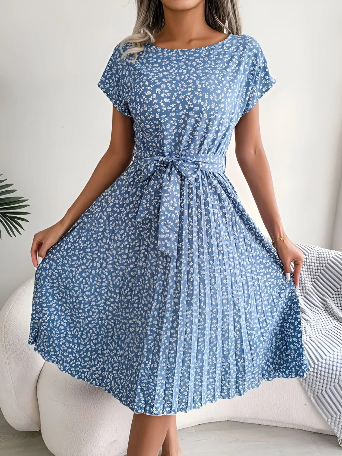 A-line dress with pleated skirt and floral pattern, worn outdoors.