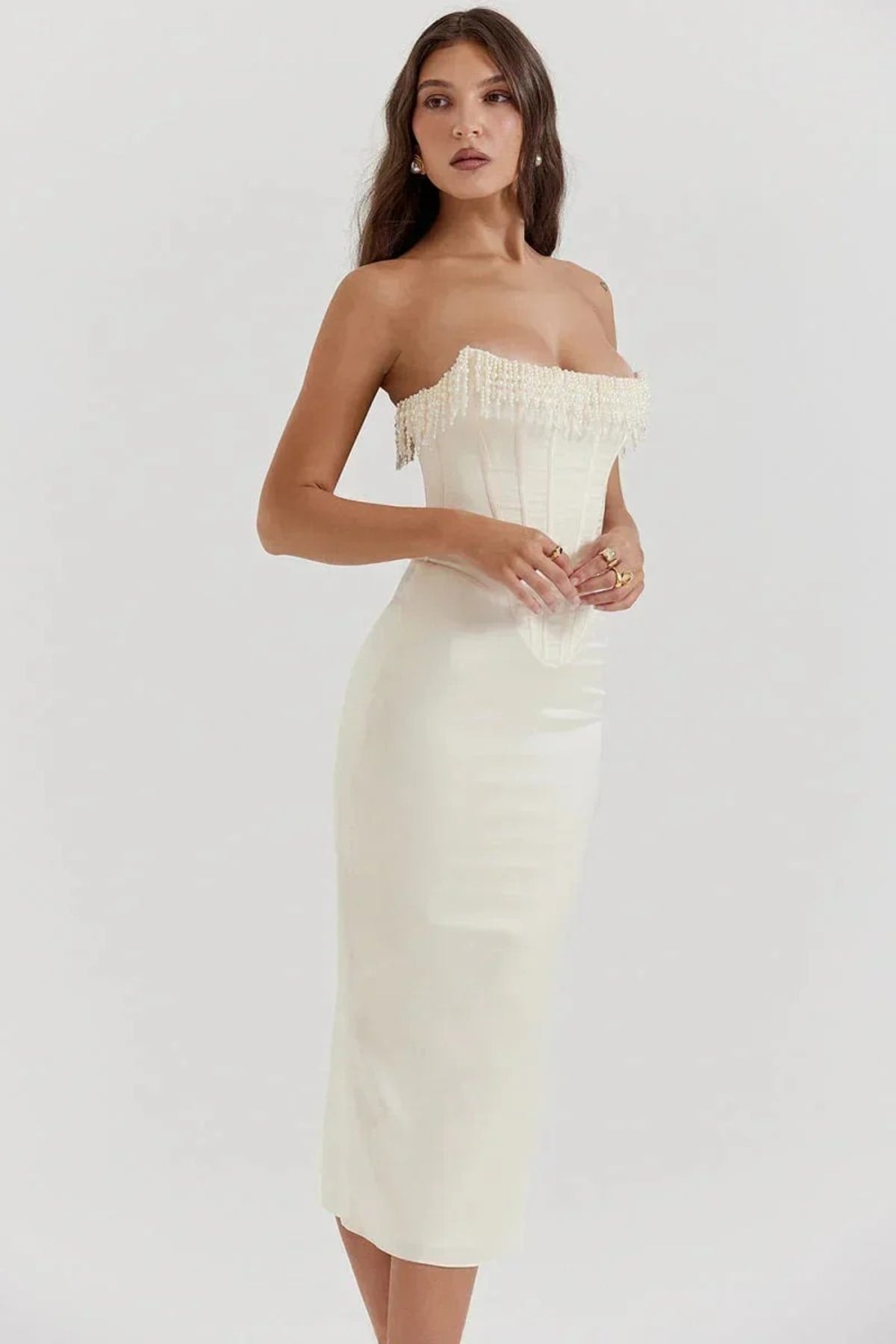 Woman wearing strapless midi dress with pearl and beaded fringe.