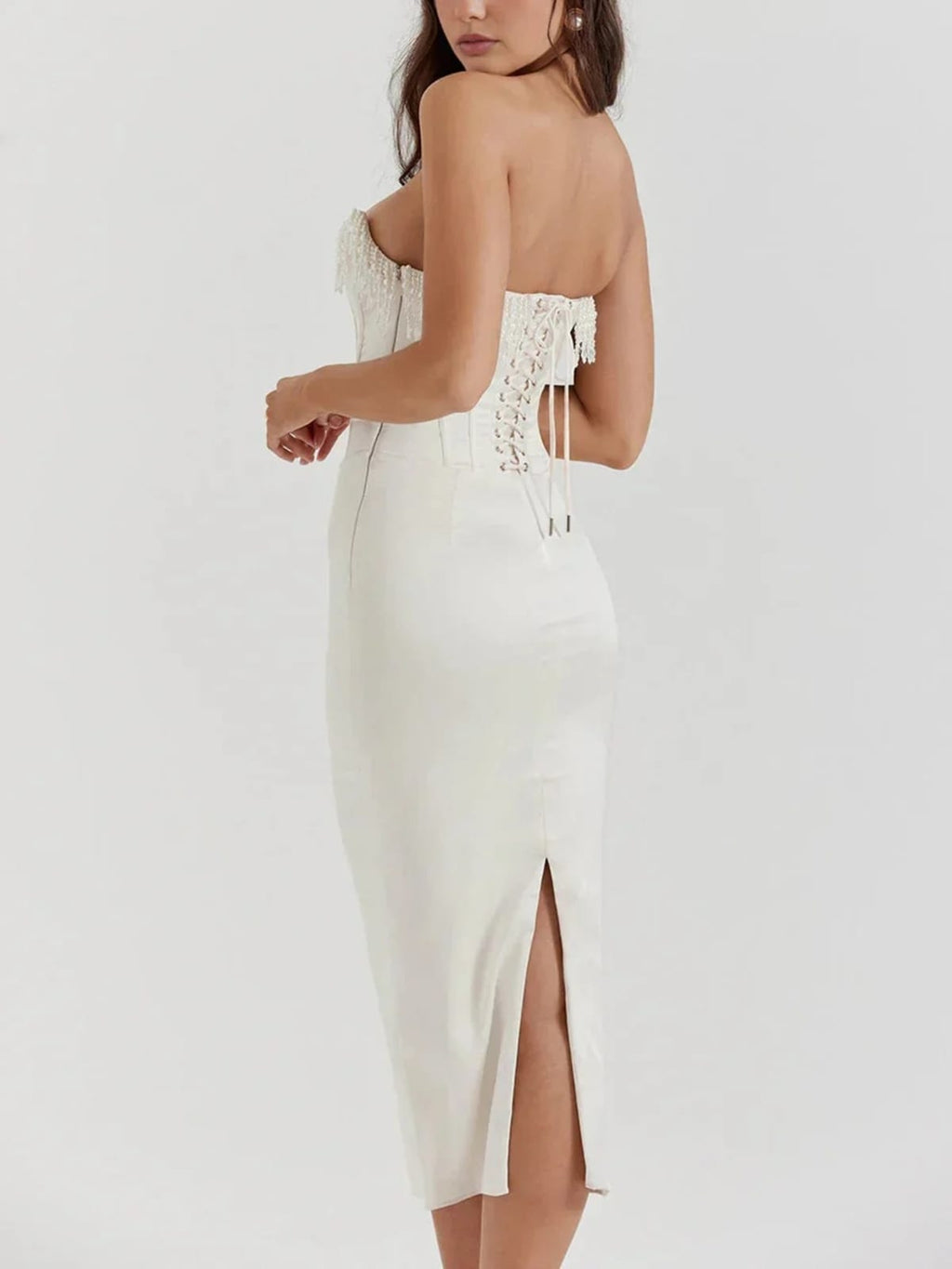 Woman wearing strapless midi dress with pearl and beaded fringe.