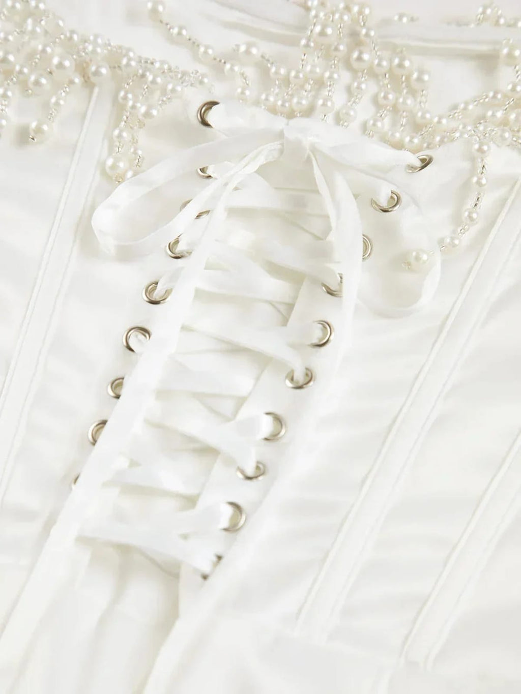 Woman wearing strapless midi dress with pearl and beaded fringe.