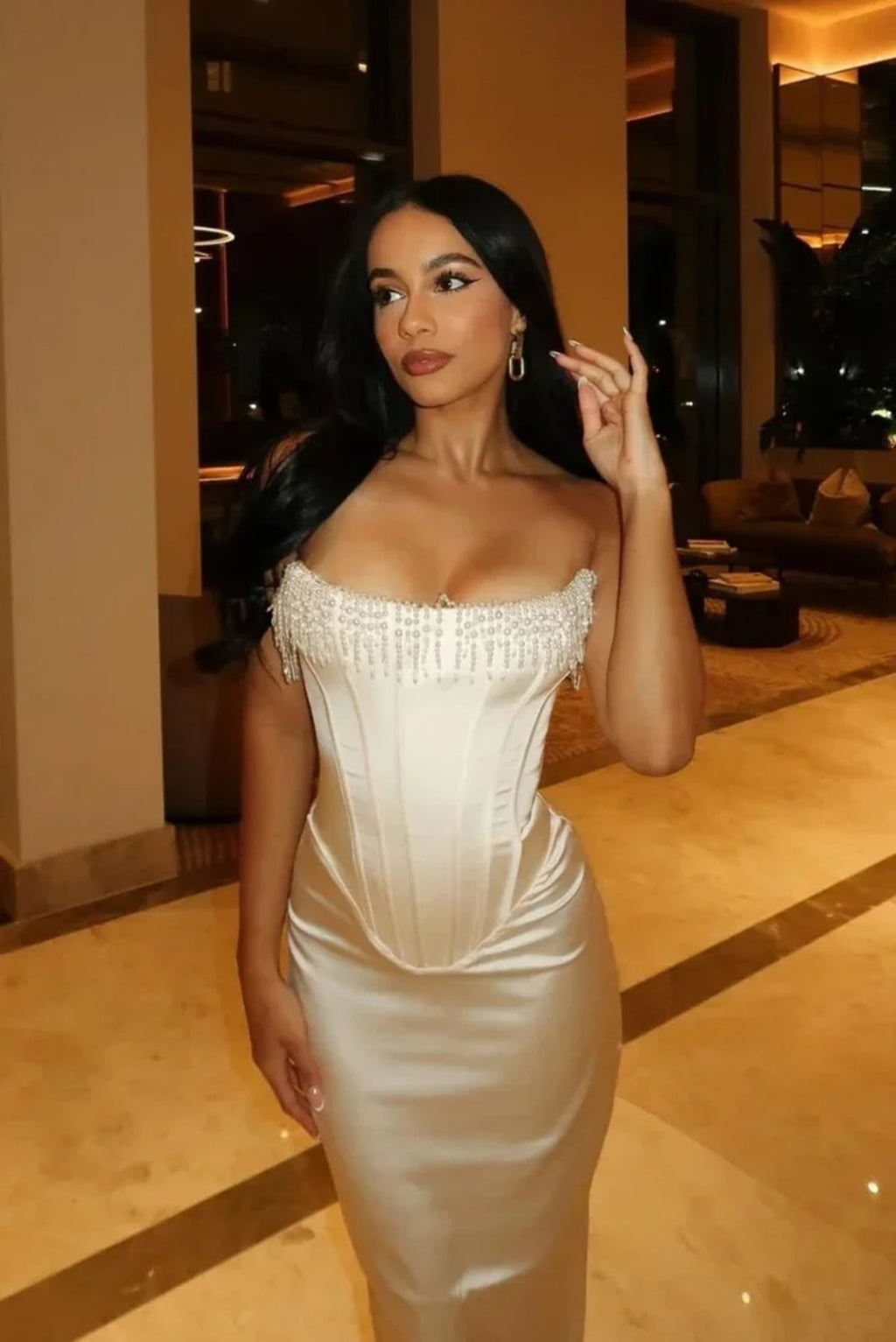 Woman wearing strapless midi dress with pearl and beaded fringe.