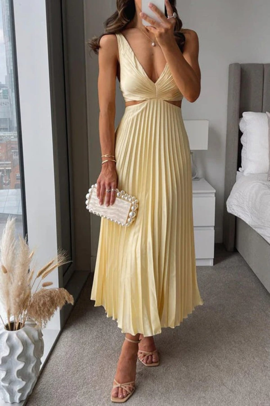 Woman in a pleated midi dress with V-neck and cut-outs.