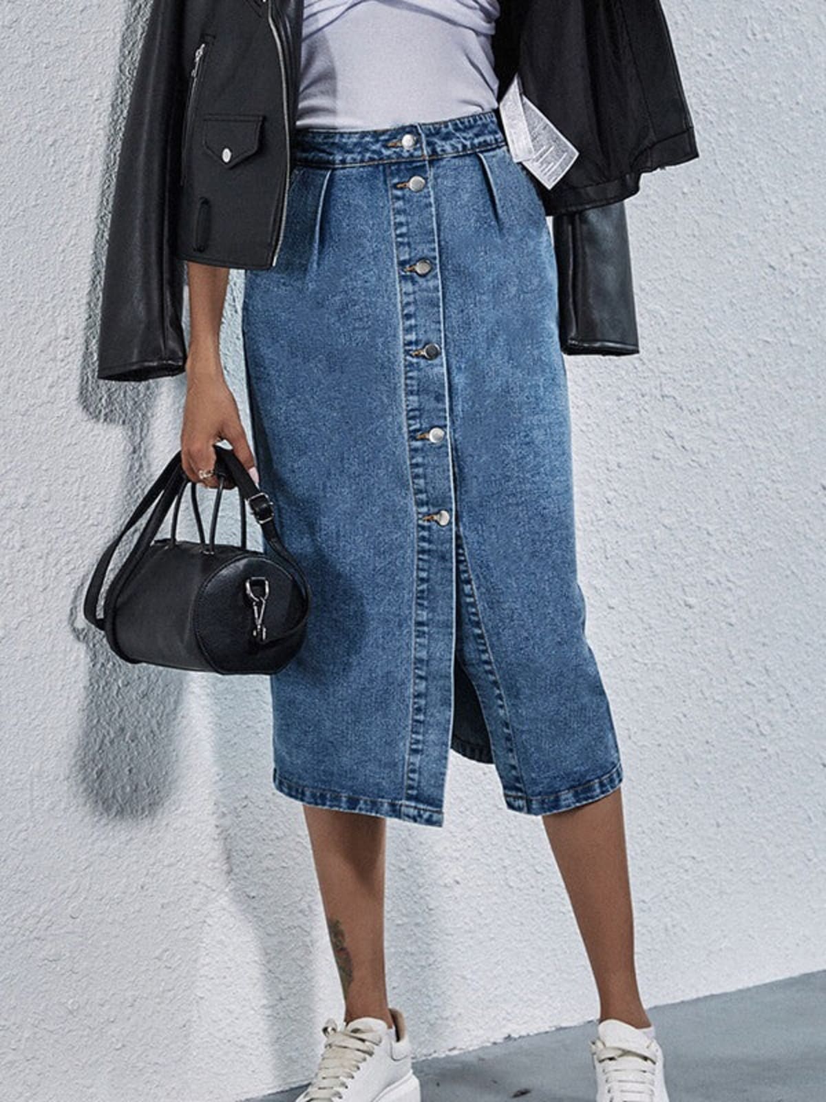 Woman wearing pleated denim midi skirt with buttons.