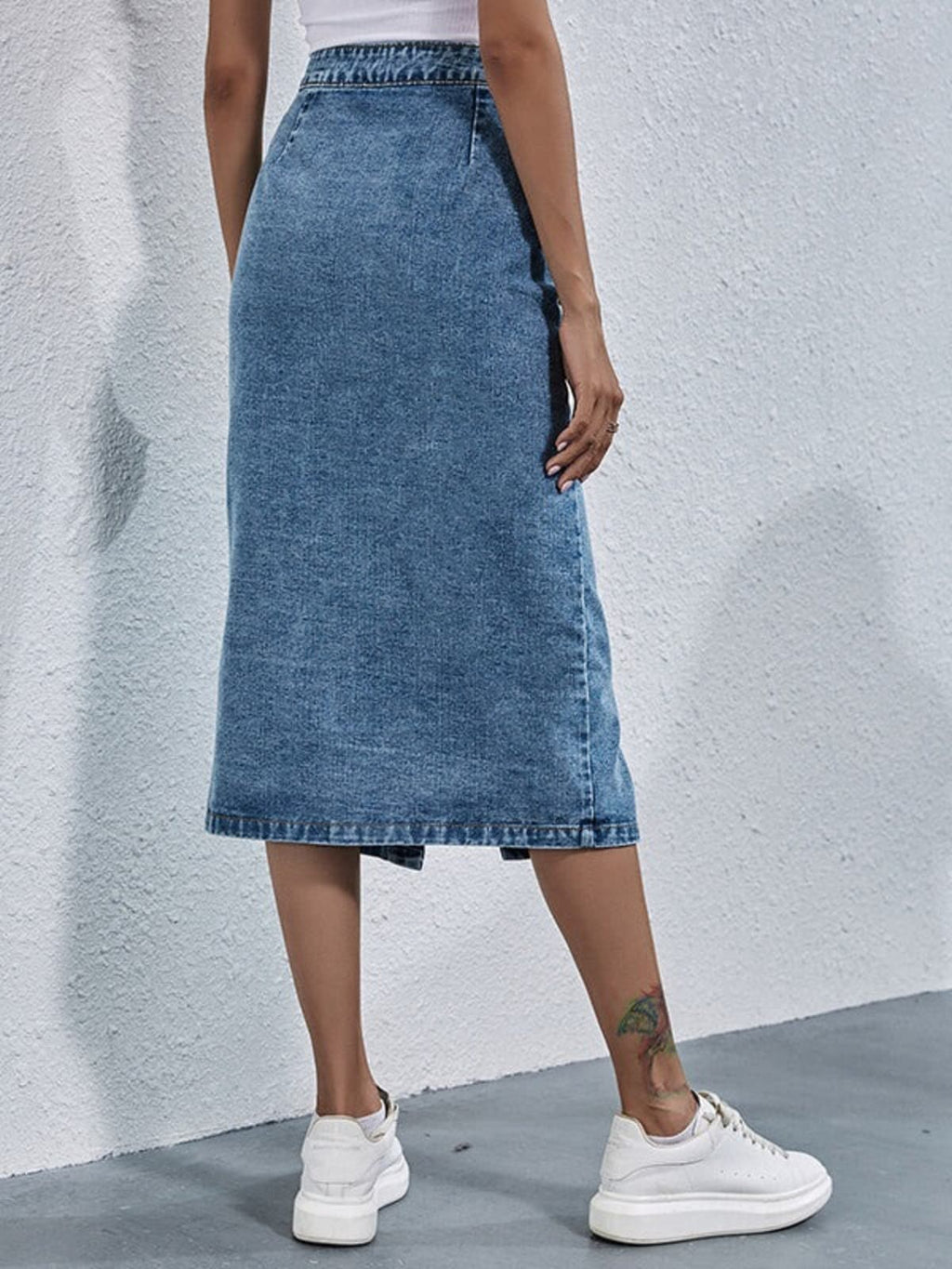 Woman wearing pleated denim midi skirt with buttons.