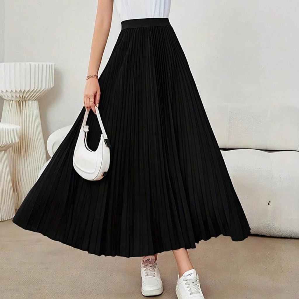 Model wearing a high-waisted pleated midi skirt with a white top and sneakers.