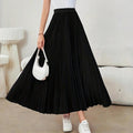 Model wearing a high-waisted pleated midi skirt with a white top and sneakers.