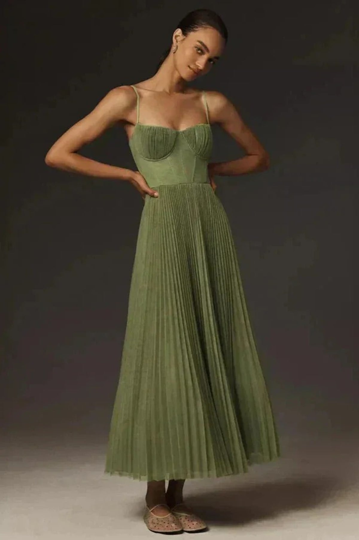 Woman wearing a sage green bustier midi dress with pleats.