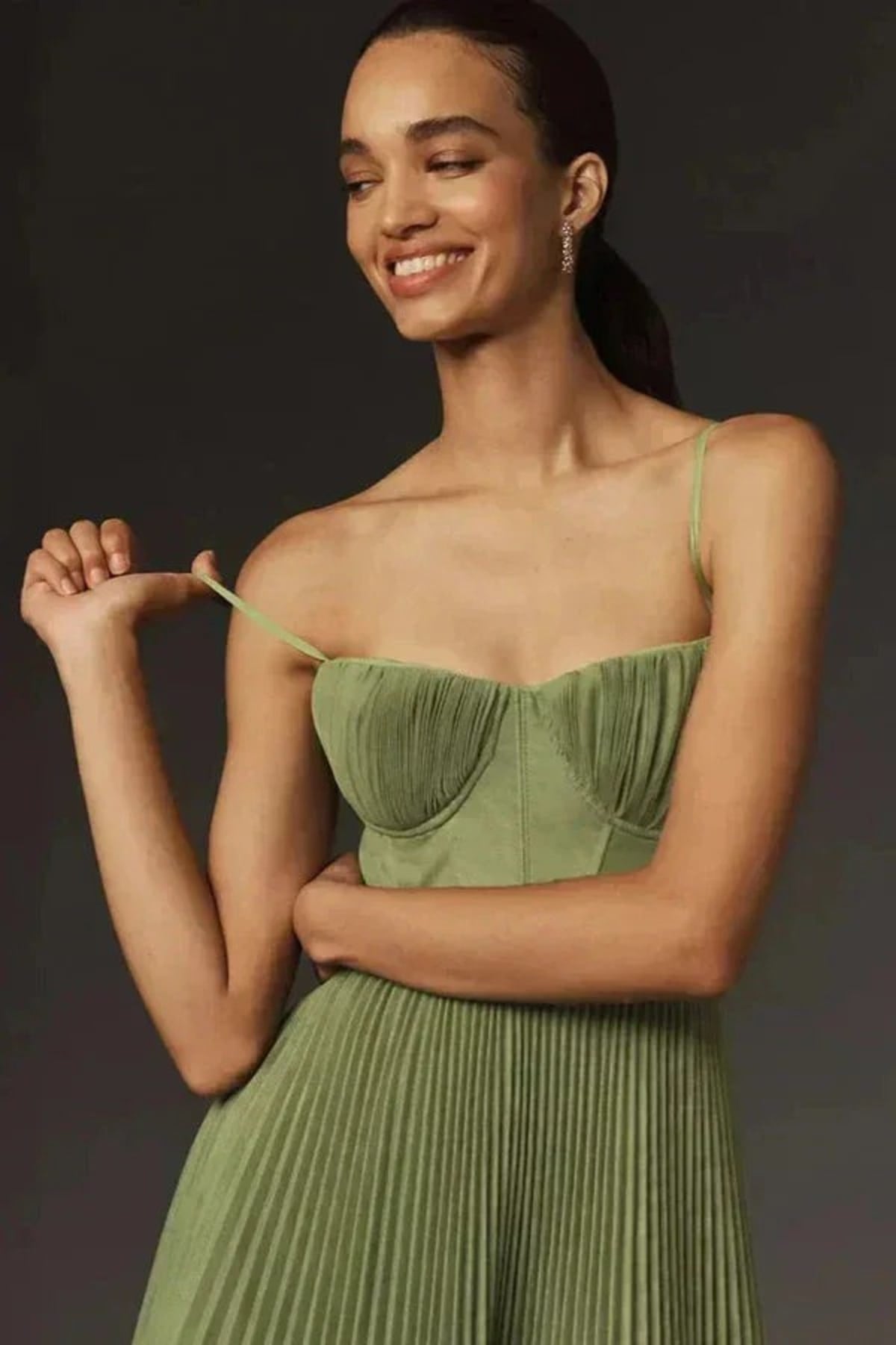 Woman wearing a sage green bustier midi dress with pleats.