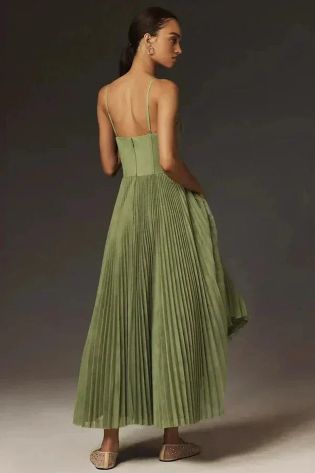 Woman wearing a sage green bustier midi dress with pleats.