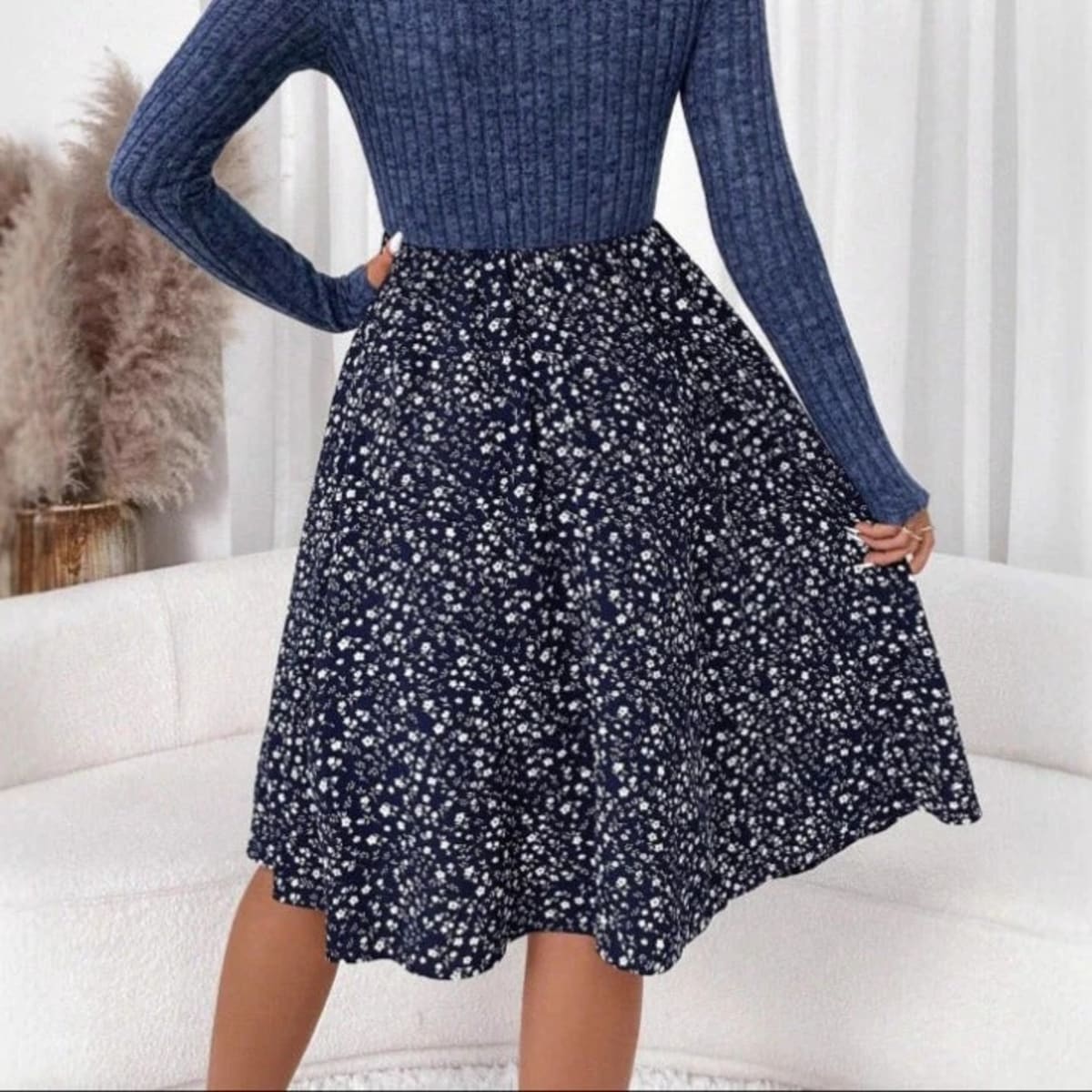 Woman wearing ribbed knit floral A-line midi dress, seated.