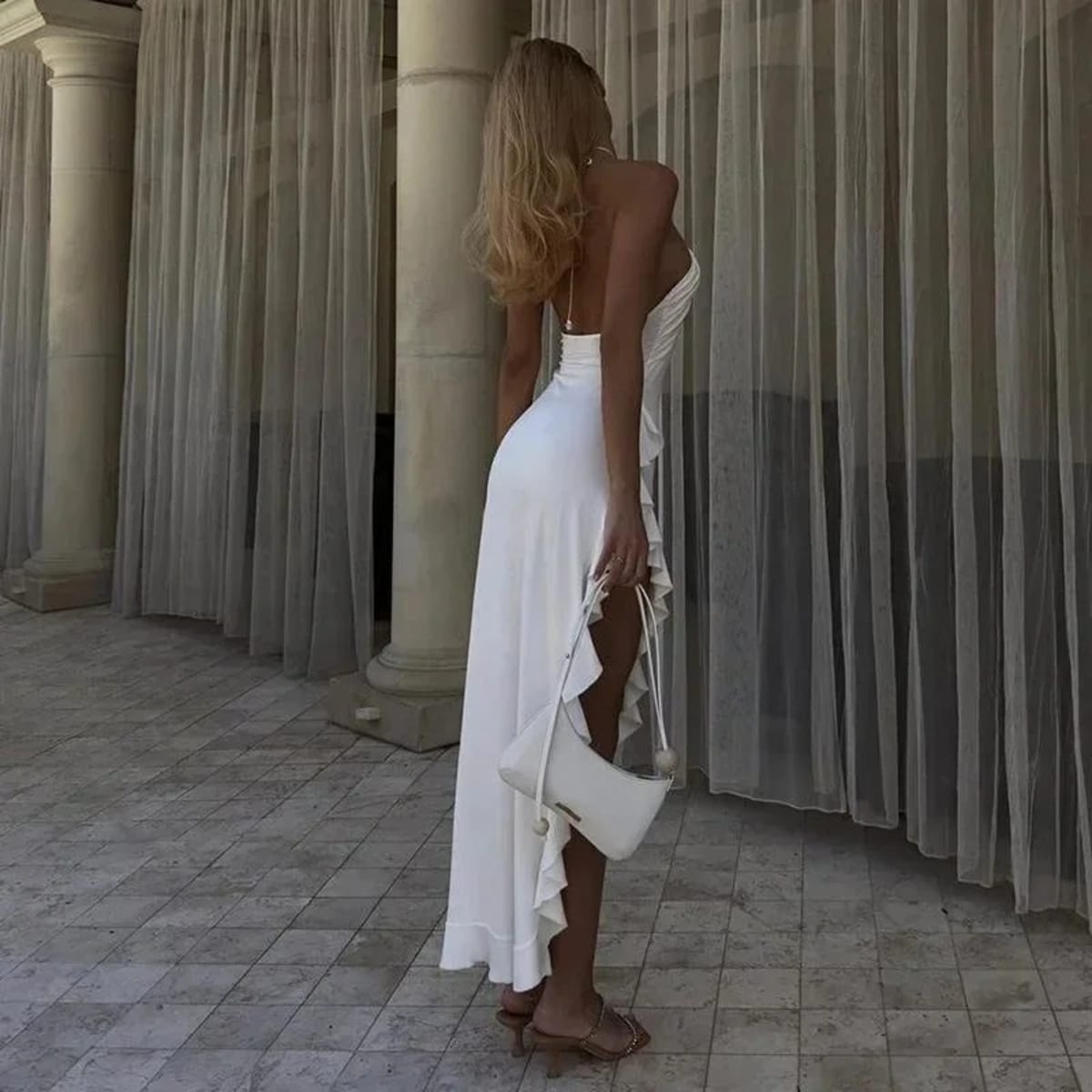 Woman on staircase wearing asymmetrical ruffled halter maxi dress