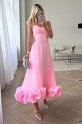 Woman in spaghetti strap midi dress with ruffled hem and fitted bodice.