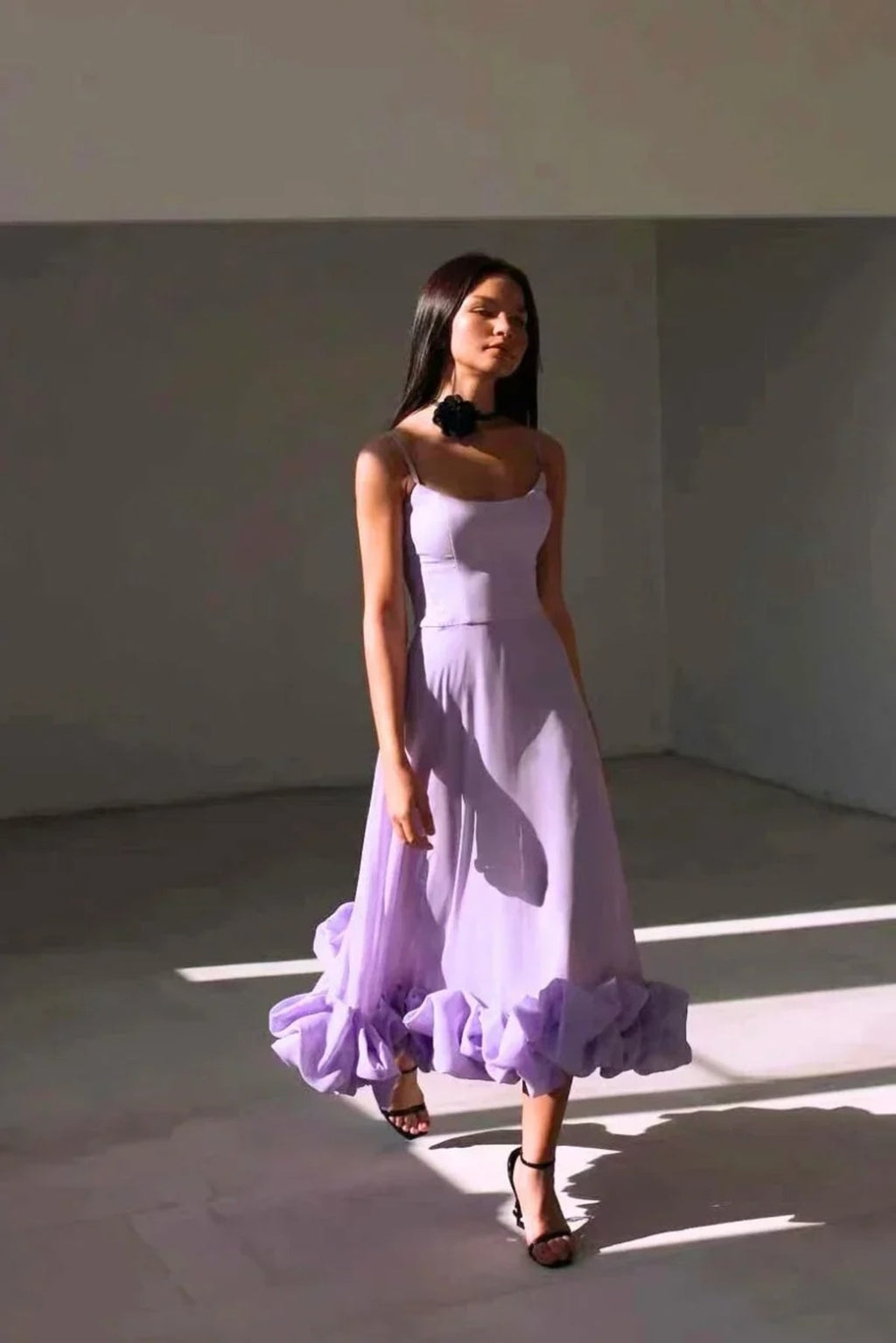 Woman in spaghetti strap midi dress with ruffled hem and fitted bodice.