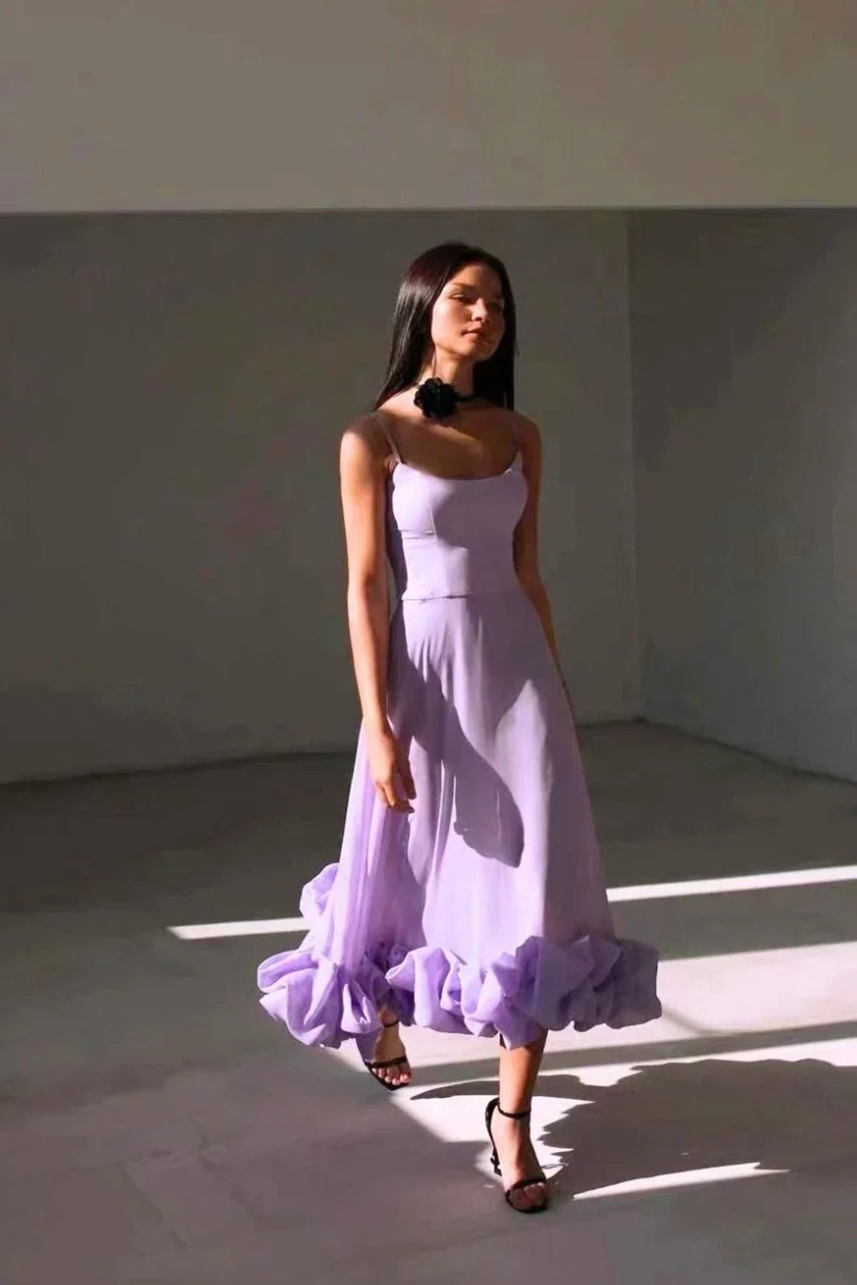 Woman in spaghetti strap midi dress with ruffled hem and fitted bodice.
