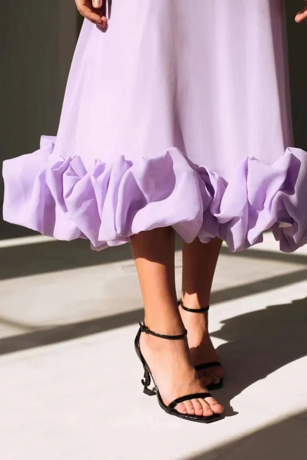 Woman in spaghetti strap midi dress with ruffled hem and fitted bodice.