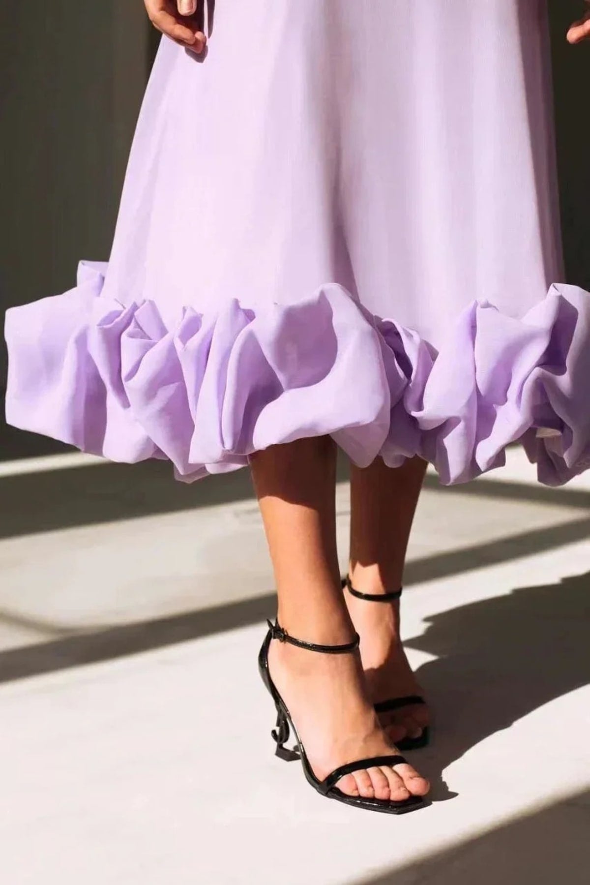 Woman in spaghetti strap midi dress with ruffled hem and fitted bodice.