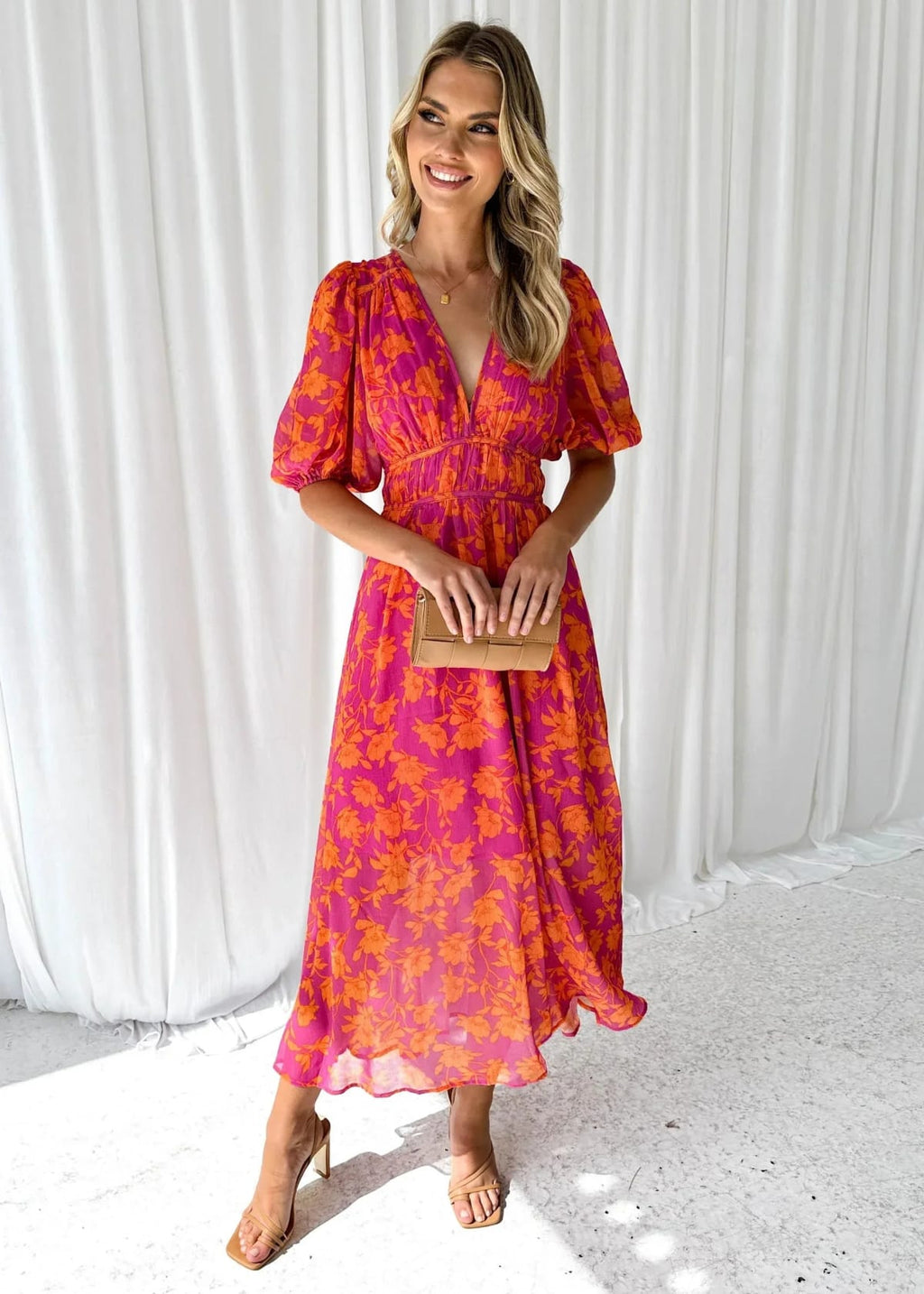 Woman modeling vibrant floral midi dress with V-neck and puff sleeves.