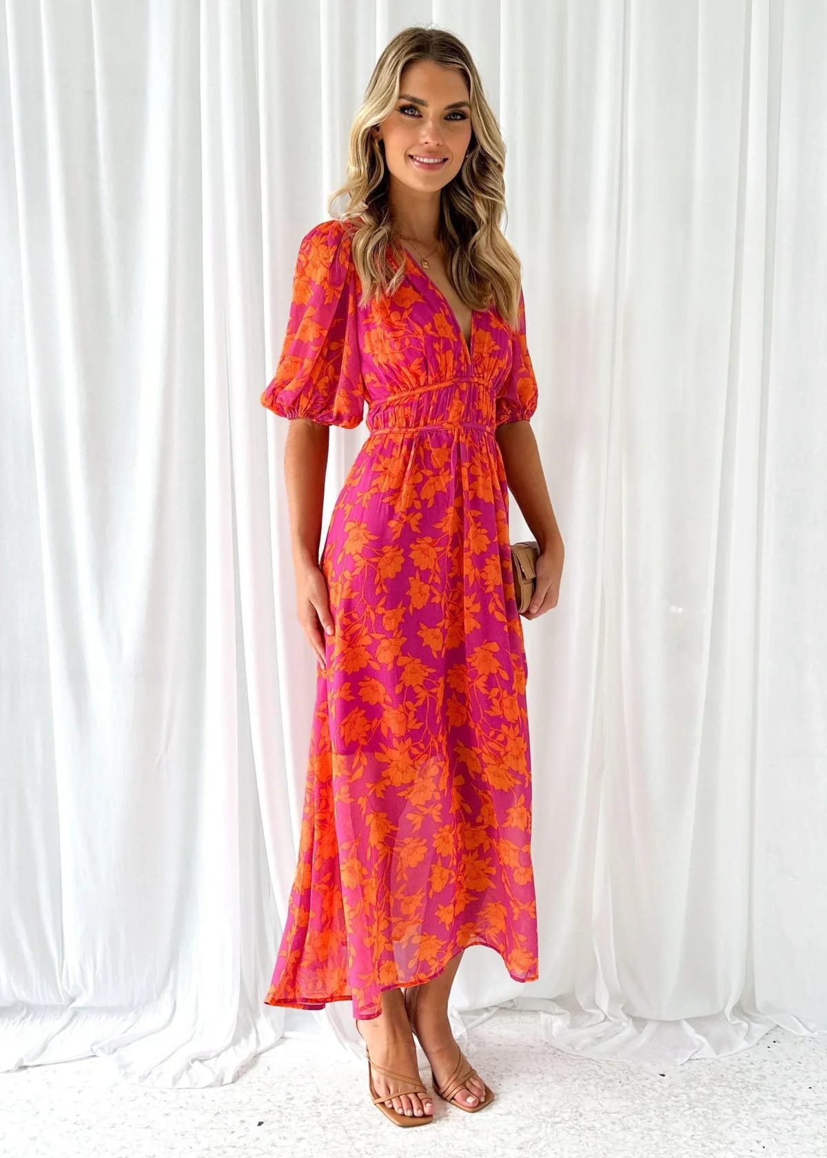 Woman modeling vibrant floral midi dress with V-neck and puff sleeves.