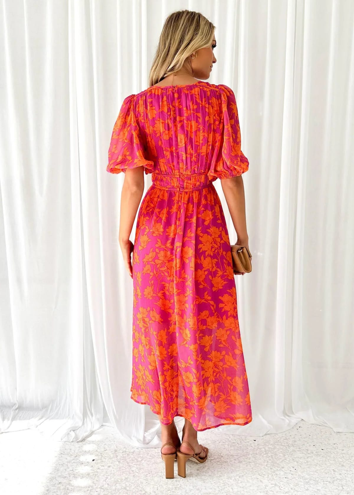 Woman modeling vibrant floral midi dress with V-neck and puff sleeves.